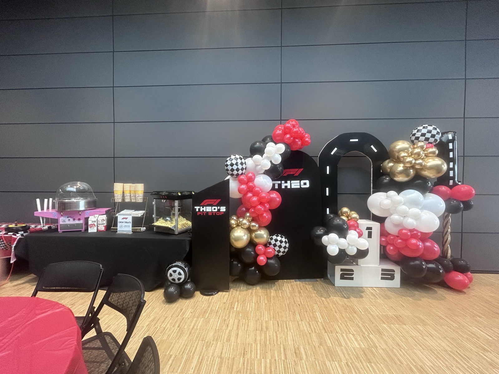 A race-car themed birthday with a tunnel backdrop, checkered flags, and a candy cart