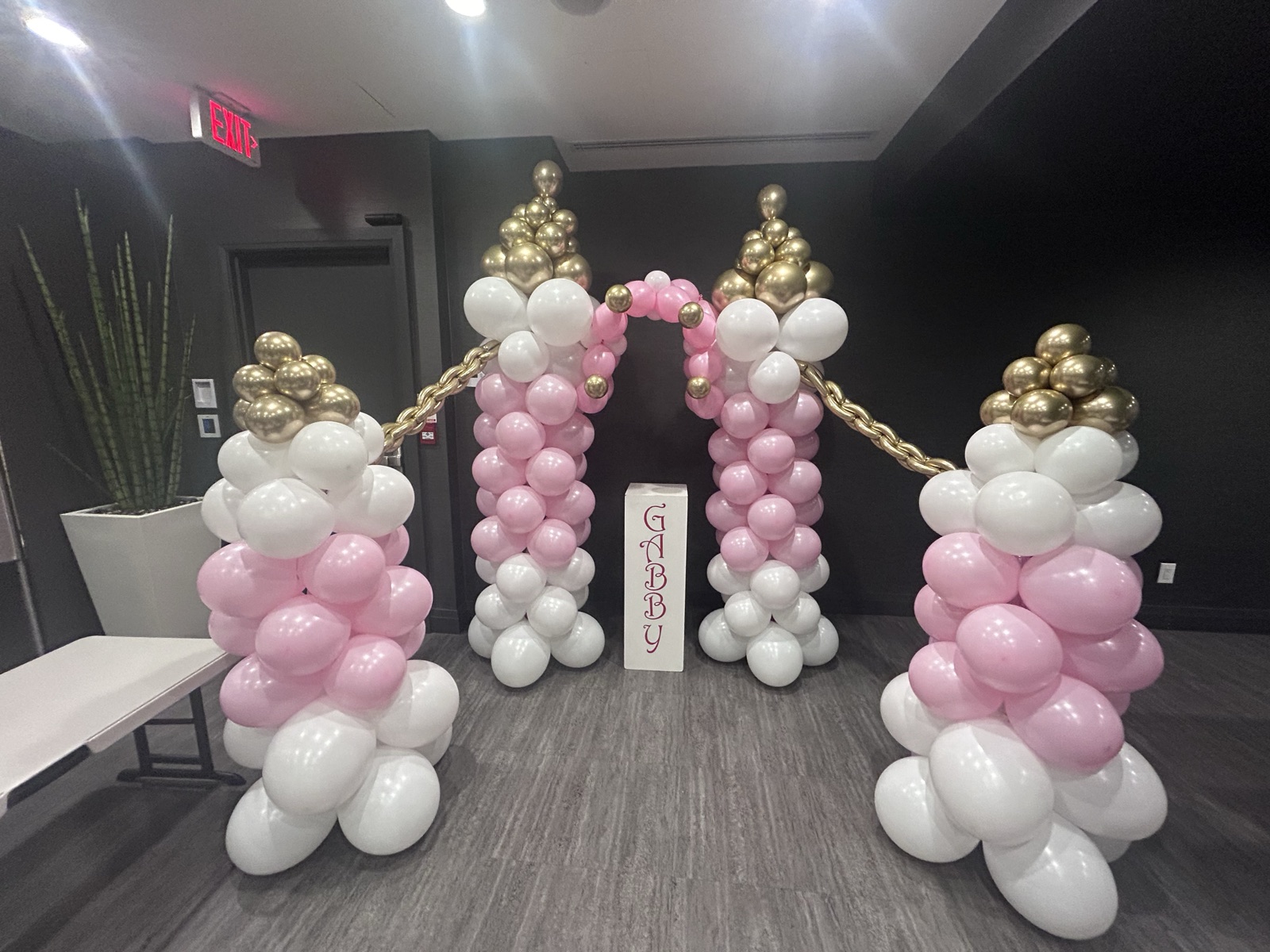 Pink, white, and gold balloon columns framing a welcome sign